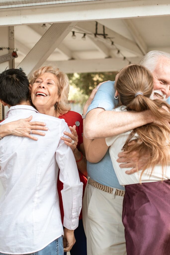 A joyful family reunion outdoors with warm hugs and smiles under a wooden pergola.