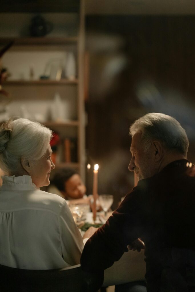 Senior couple enjoying a warm family dinner by candlelight, creating a cozy and intimate atmosphere.